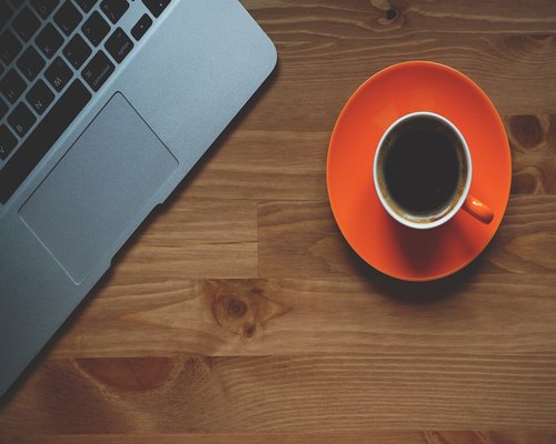 An office desk surface during a short break showing a coffee cup away from the screen