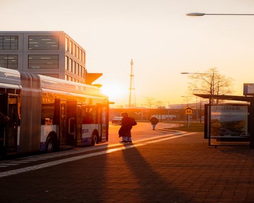 A person walking down a clean city street near a transit stop during afternoon hours